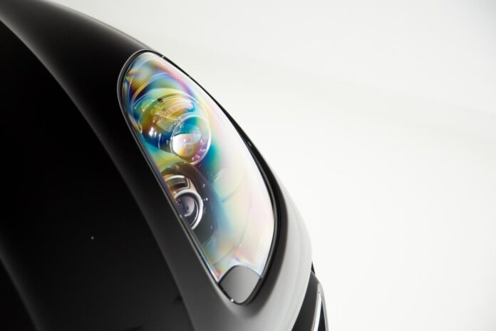 closeup-shiny-headlight-black-luxury-car-isolated-white-background