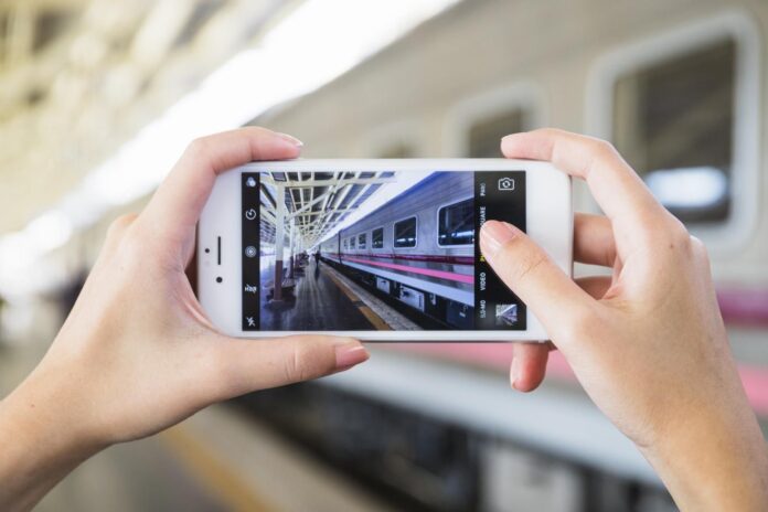 hands-holding-smartphone-platform-near-train